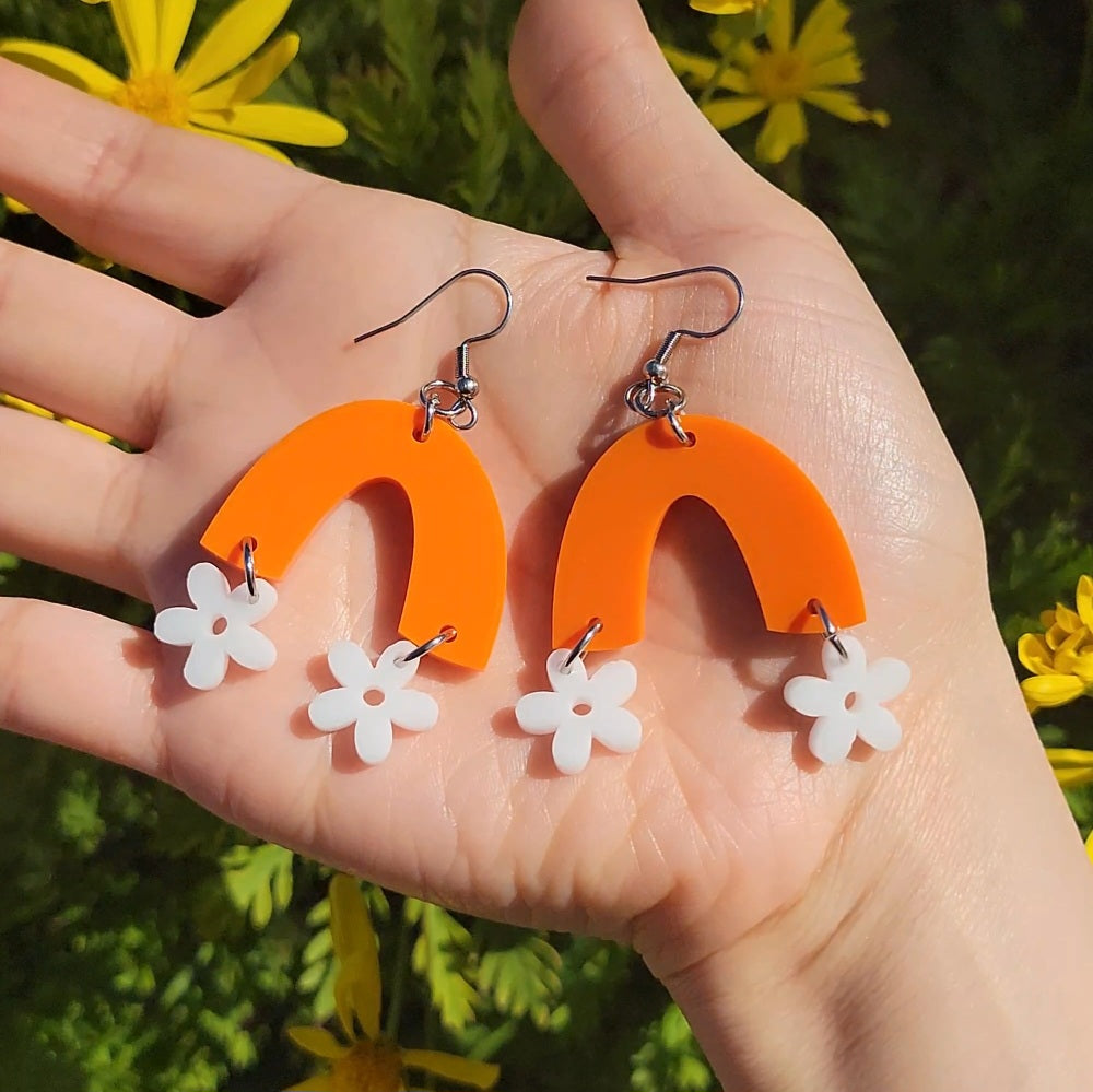 small white flowers hanging from orange arch earrings
