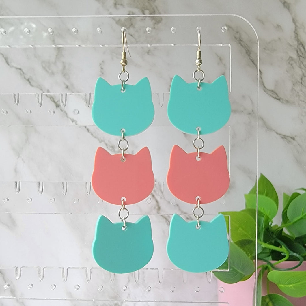 Cat head earring drop dangles. Each dangle earring has 3 cute cat head shapes. first and third cat face is mint color, second is pink.